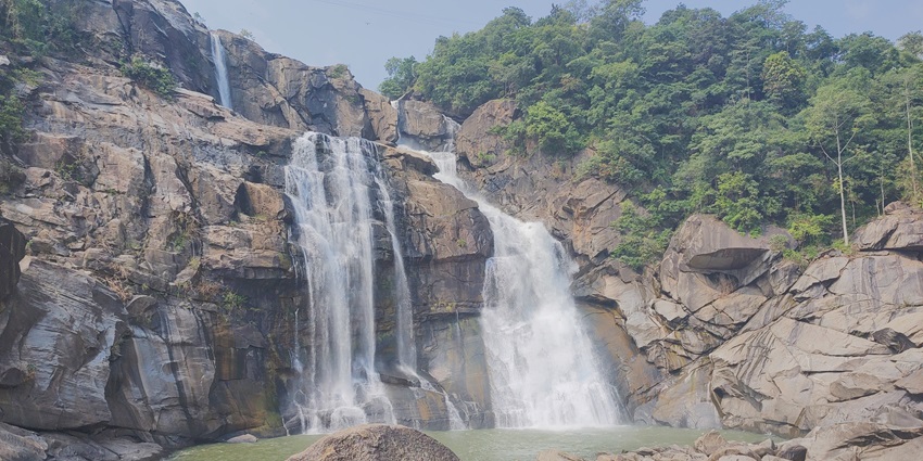 -A scenic view of water cascading down a waterfall into a rocky pond at the Hundru Falls