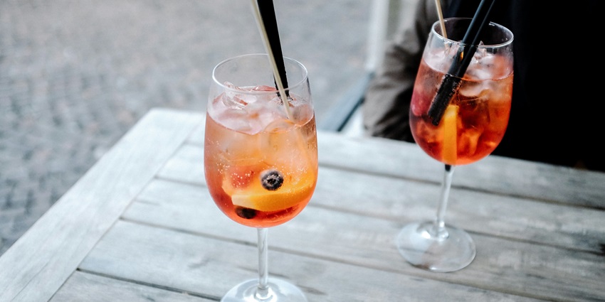 Image of two clear glassed with red colour cocktail drinks in its ice cube and a straw for sipping