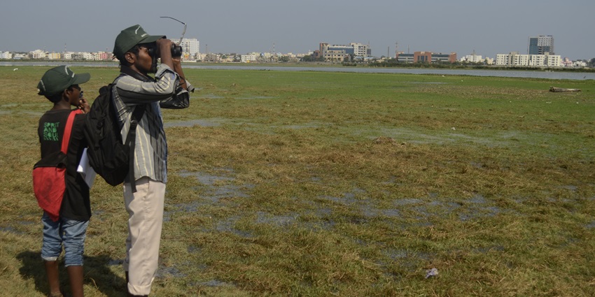 A picture of 2 birdwatchers observing birds with a pair of binoculars and collecting important information