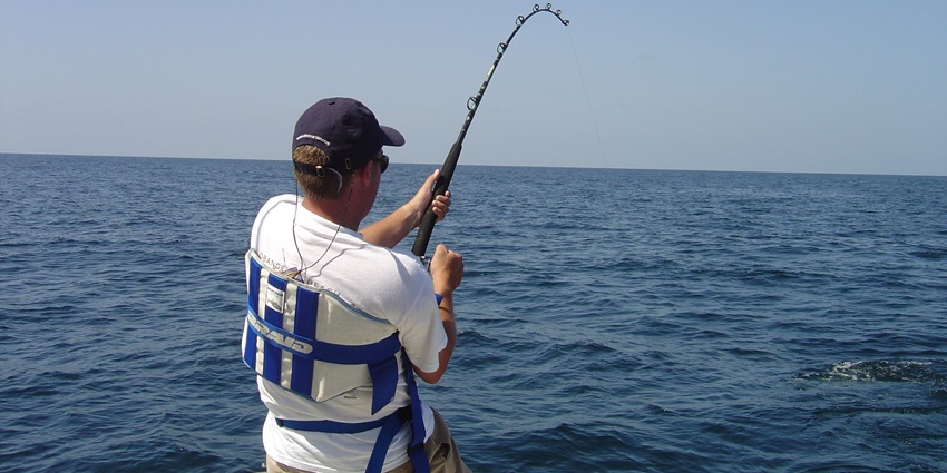 A picture of a tourist fishing from a boat in the Arabian Sea using modern fishing gear