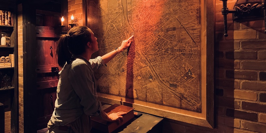 A woman using a map to identify clues at a Escape Room.