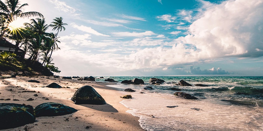 An image of a calm seaside with gentle waves, a sandy shore, and distant cliffs.