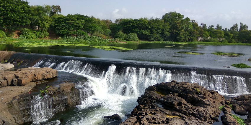 Clear water Lake hitting the rocks surrounded by the green landscape of Indori village