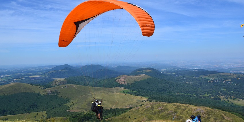 Paragliders taking off for paragliding near Pune with another person sitting at a distance.