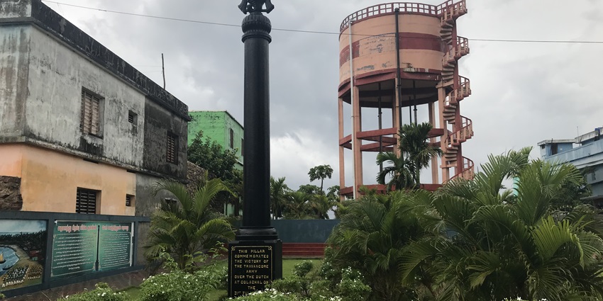 A picture of a victory pillar in Burhanpur surrounded by lush greenery and tall trees