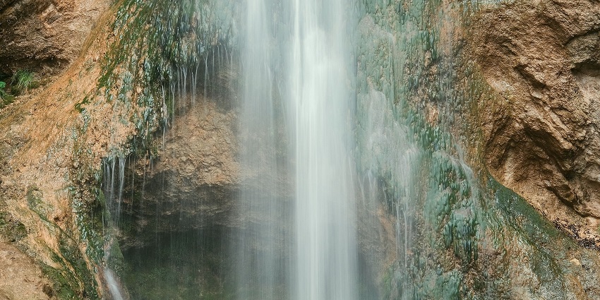 An image of Jalagamparai waterfall cascading down rocks amidst lush greenery.