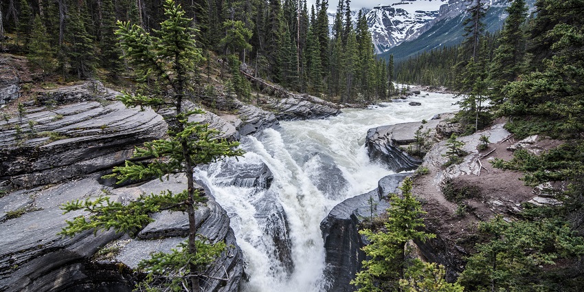 Water flows down a waterfall, crashing against rocks