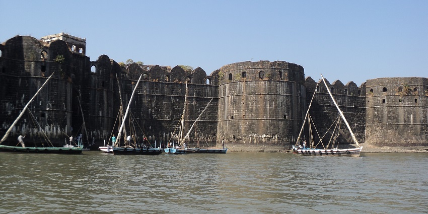 Scenic view of the Janjira fort, with a lake forefront and small boats in it