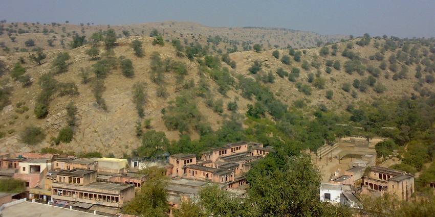 The land below Jeen Mata Hill showcases the old architecture surrounded by hills.