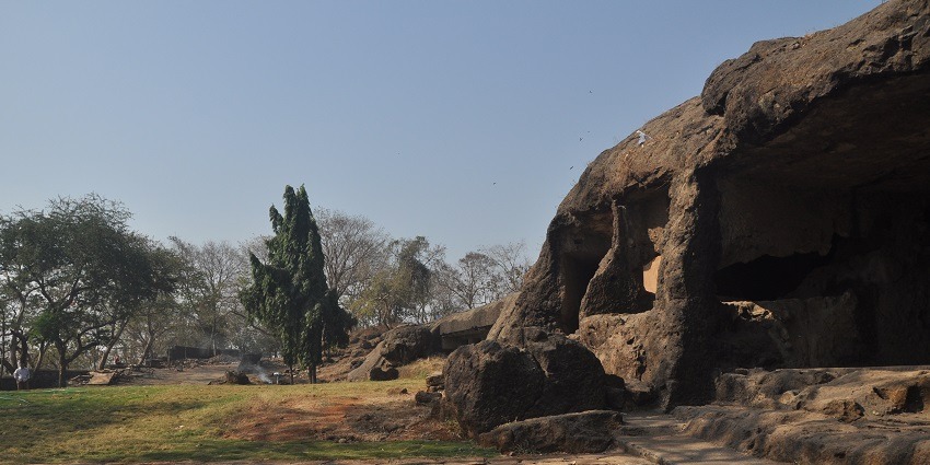 Ancient rock-cut structures outside of Jogeshwari Caves with carvings and pillars