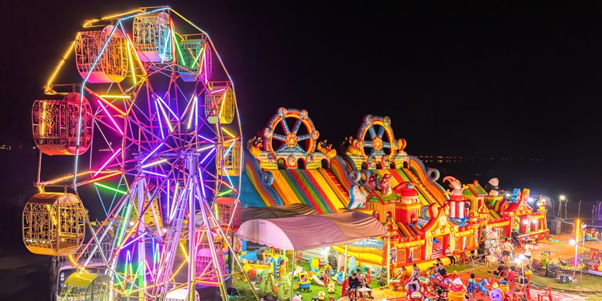 Scenes at a funfair featuring a glowing Ferris wheel and inflatable bouncing castle