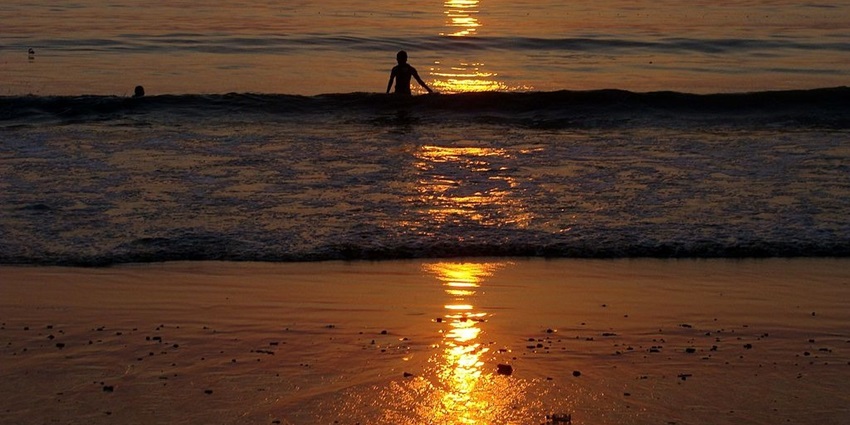 An image view of Juhu Beach with families enjoying the sunset and local street food stalls.