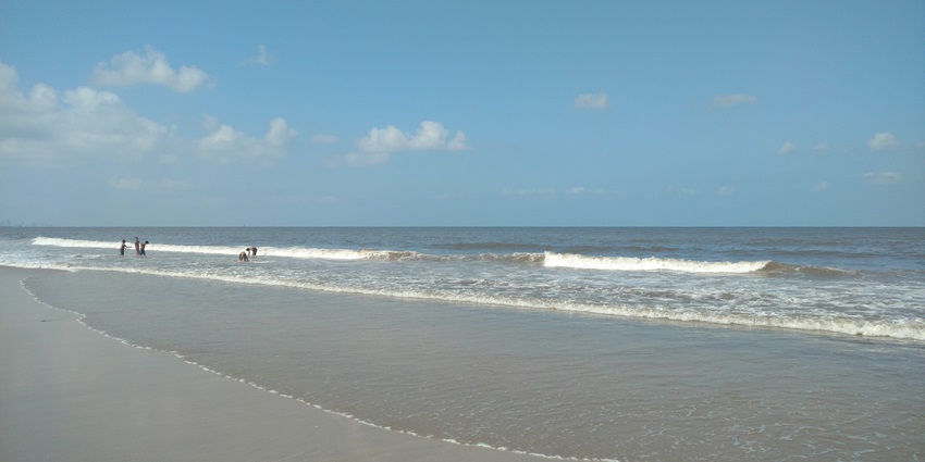 A serene Juhu Beach morning with gentle waves and soft sunlight illuminating the sand.