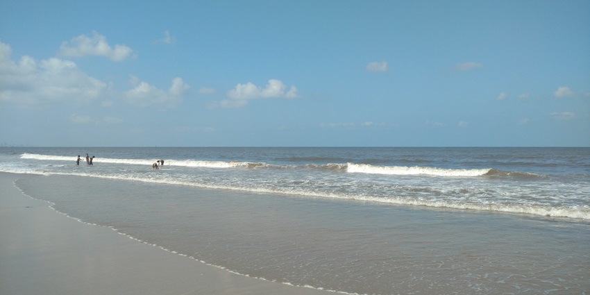A serene Juhu Beach morning with gentle waves and soft sunlight illuminating sand