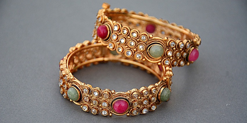 An image of two gold bangles embraced with jewels placed on a counter in Juna Bazaar.