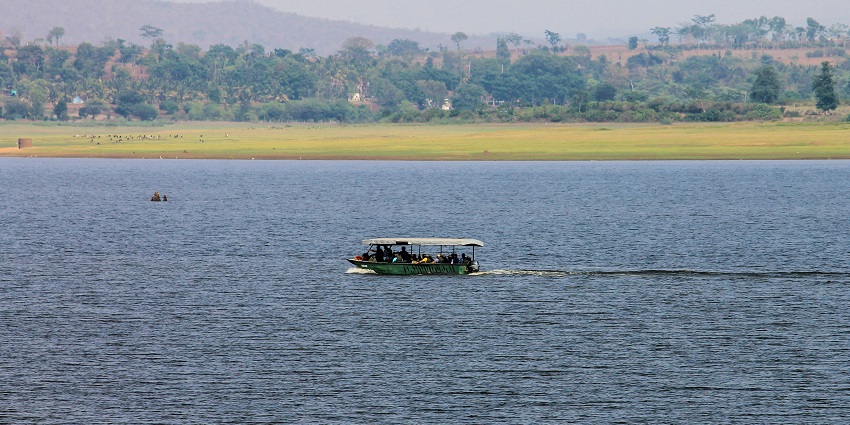 Image of Waterwoods Lodge, Kabini and lake surrounded by lush greenery under clear blue sky