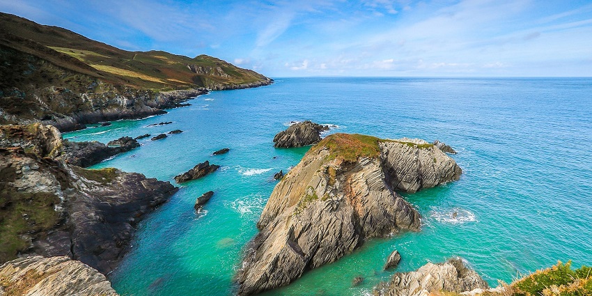 A beautiful Island in the middle of clear blue water with cliffs of rocks peeping through.