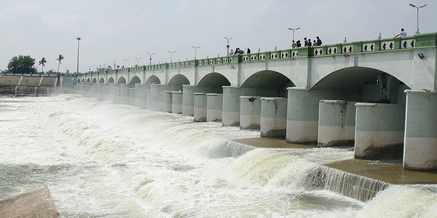 An image of the historic Kallanai Dam over the river with flowing water and greenery.