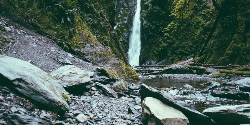 An image of a serene Kalmandavi Waterfall cascading through rocks amidst a dense green forest.