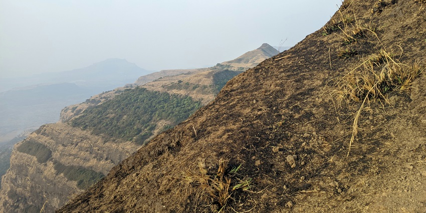 An early morning view from Kalsubai Peak with covered valleys and rolling green hills.