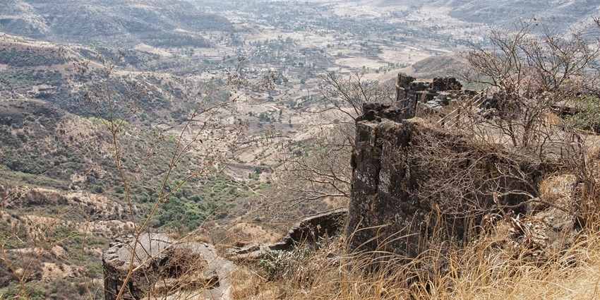View of fort bastions near Naneghat caves in Maharashtra surrounded by greenery.