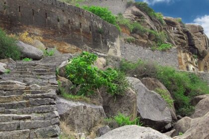 The ancient Kamandurg Fort with a tall mountain backdrop, surrounded by greenery.