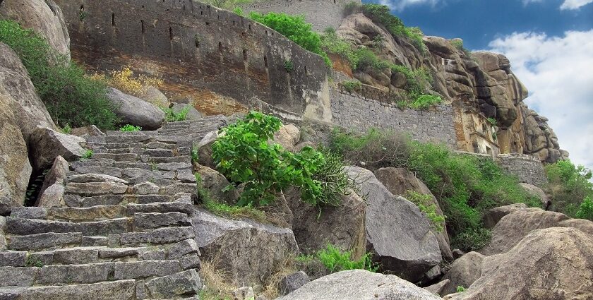 The ancient Kamandurg Fort with a tall mountain backdrop, surrounded by greenery.