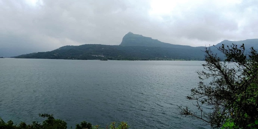 A picture of pawna lake surrounded by lush greenery