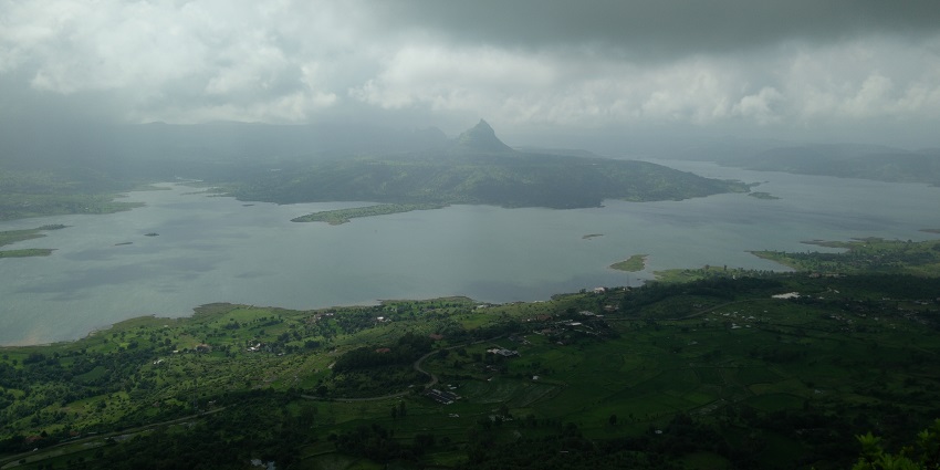 From the hill of Tikona Fort with Pawna Lake surrounded by hills and clouded sky in view