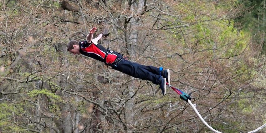 A picture of a person enjoying bungee jumping in Maharashtra with green forest in the surroundings