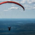 Paraglider flying solo high above Mont Valin and the green landscapes of Quebec