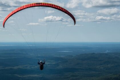 Paraglider flying solo high above Mont Valin and the green landscapes of Quebec