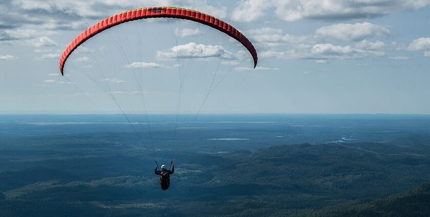 Paraglider flying solo high above Mont Valin and the green landscapes of Quebec