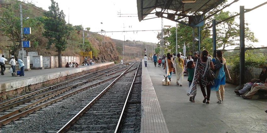 Kamshet Station in India with a signboard, displaying its name and surrounded by greenery