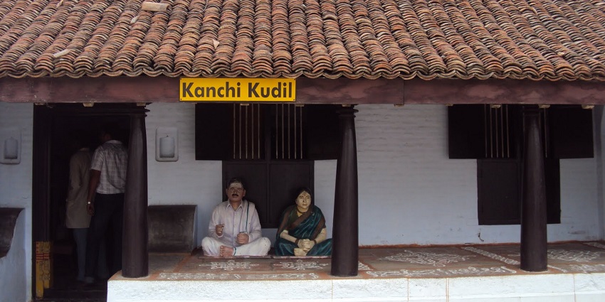 Outside of Kanchi Kudil heritage home with classic architecture and two statues on complex