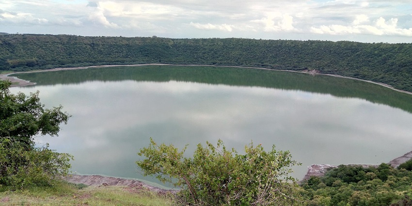 A scenic view of a broad lake surrounded by mountains and greenery at Kapshi Lake.