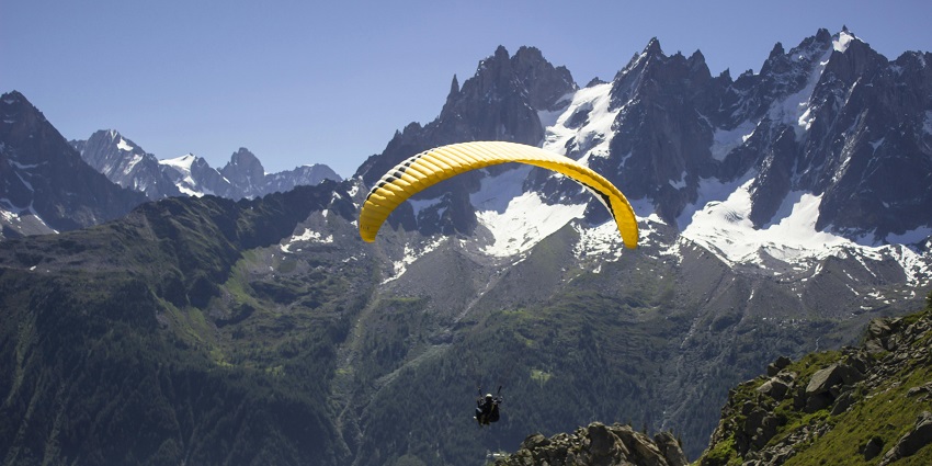View of a tourist paragliding with snow covered mountains in the background