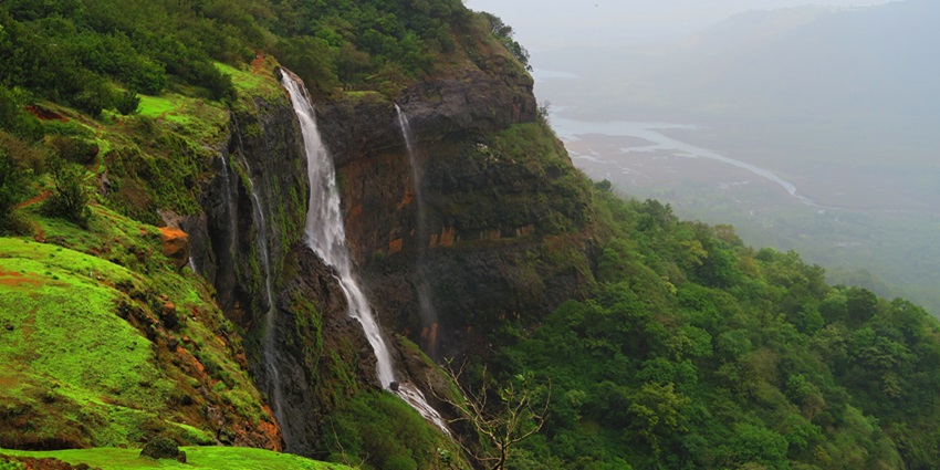 Matheran waterfall cascading through lush green hills during the monsoon season.