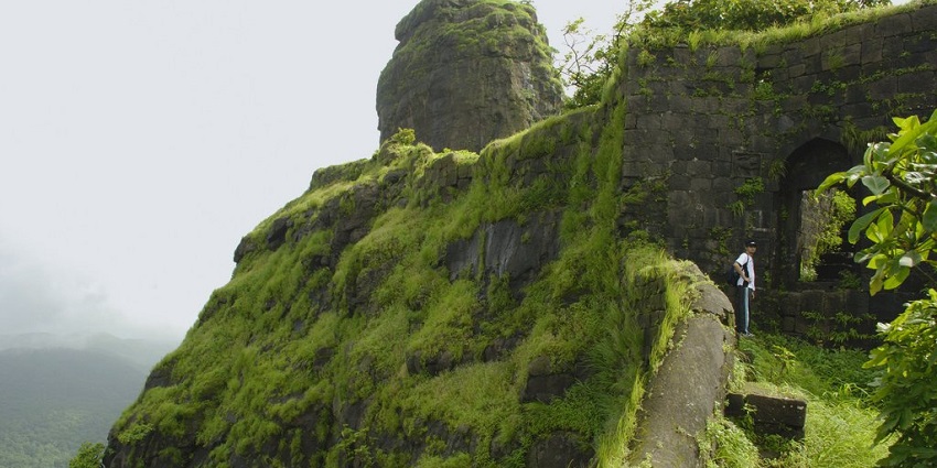 The entrance of the Karnala Fort, tall walls covered with green moss