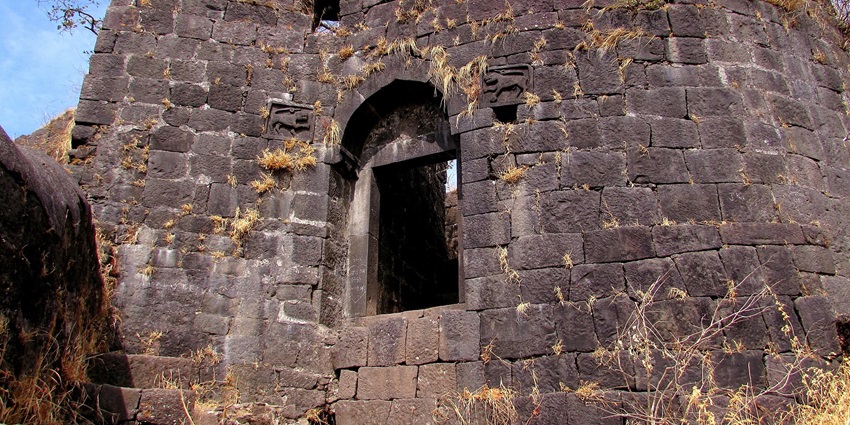 The gateway of Karnala Fort, surrounded by green hills, is a tourist attraction near Dronagiri Fort.