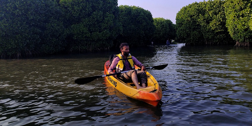 A picture of a kayaker sitting on a yellow kayak in the quiet waters of Tarkarli.