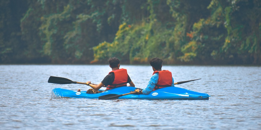 An image of kayakers paddling through calm waters surrounded by greenery.