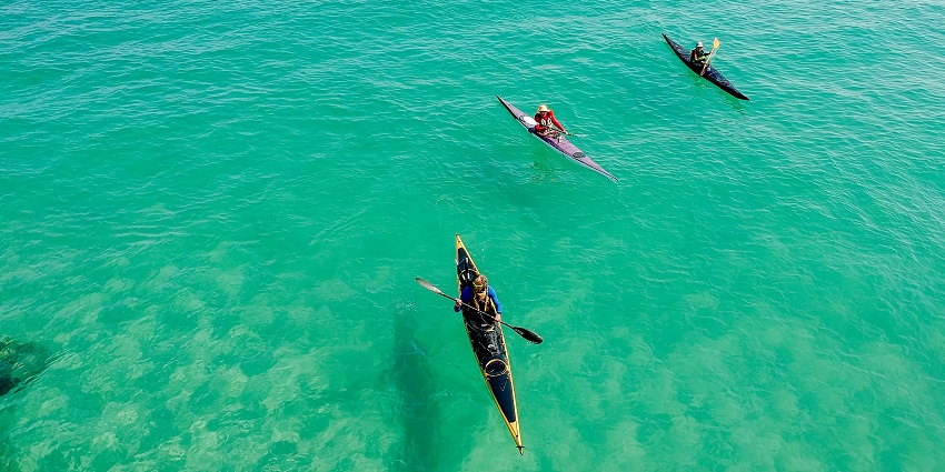 Three people kayaking on the calm and the most beautiful waters of Mandwa Beach.