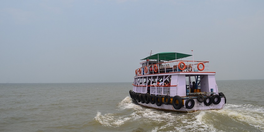 A glimpse of the Mandwa Beach featuring a boat sailing on the shimmering waters.