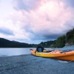 A kayak on the shore of scenic waters of Pune, surrounded by lush hills in Maharashtra