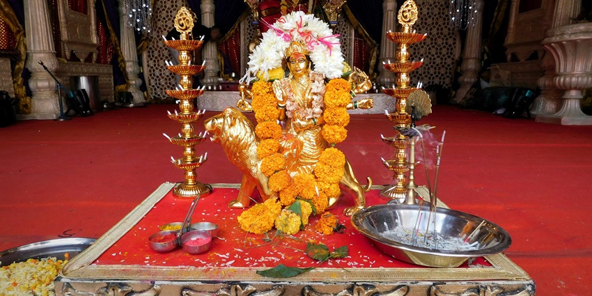 A small golden idol of Devi Maa is placed in a temple in front of a bigger idol of the Goddess.