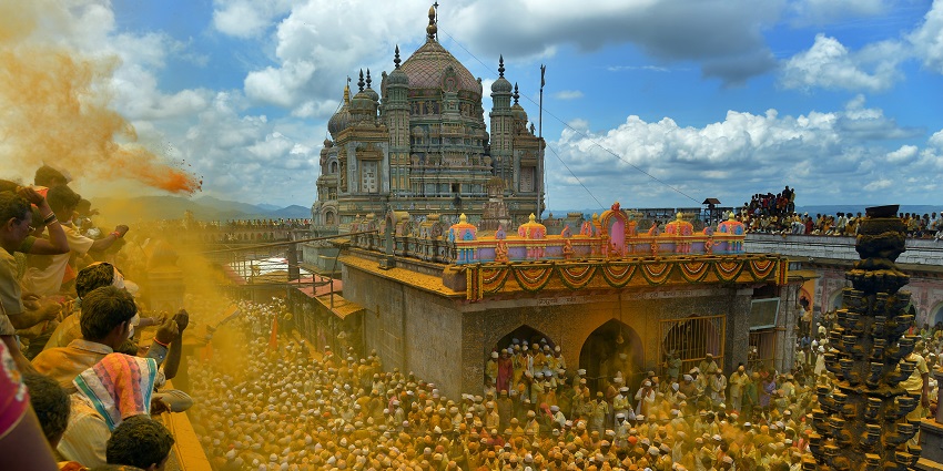 The Khandoba Temple features a bright yellow facade with ornate carvings and a central dome