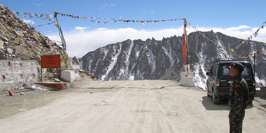 Khardung La Pass checkpoint with army presence, showcasing rugged mountain terrain.