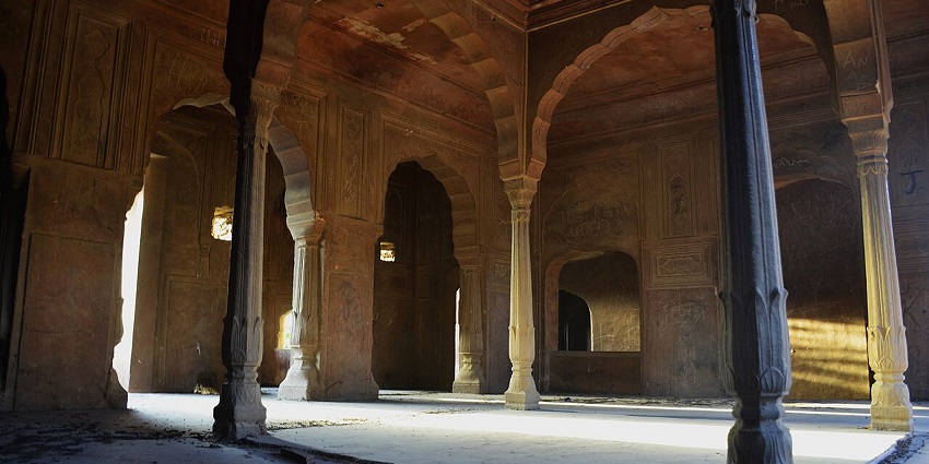 Khetri Mahal's inside architecture with patterns and arched windows in a dusty landscape.