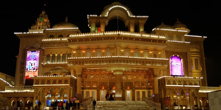 Kingdom of Dreams illuminated at night with many lights and people on the steps.